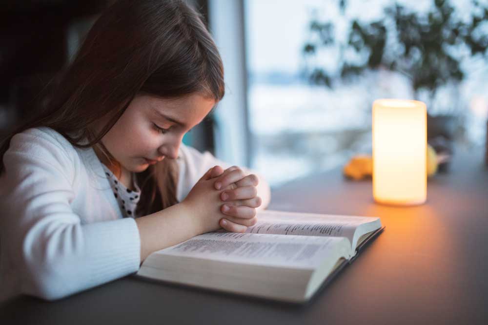 Little girl reading Bible and praying